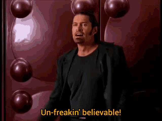 a man in a suit says " un-freakin ' believable " in front of a red wall
