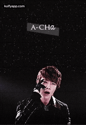 a young man is standing in front of a starry sky with a sign that says a-cha .