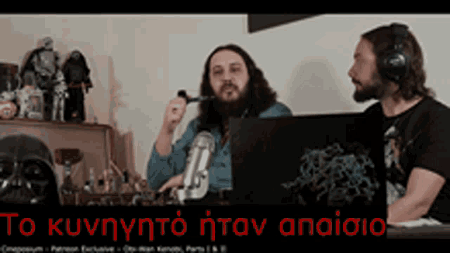 two men are sitting in front of a microphone with a sign that says to κυνηγωτο ηταν αναισιο