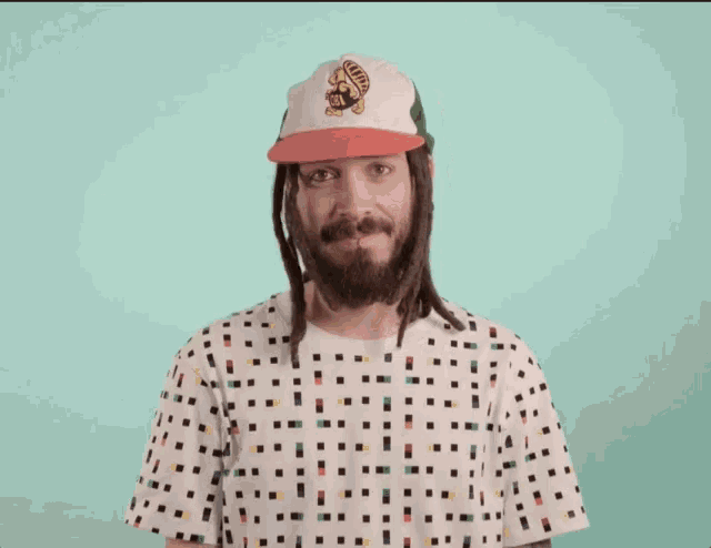 a man with dreadlocks wearing a hat and a shirt that says ' rasta ' on it