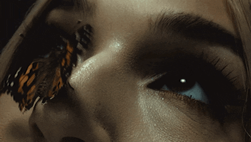 a close up of a woman 's face with a butterfly on her eye