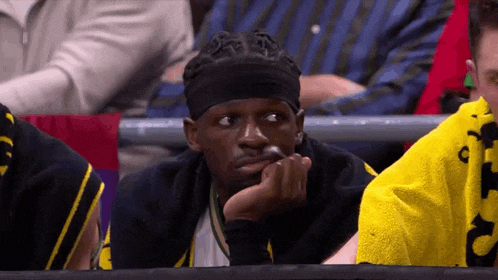 a man wearing a headband is sitting in the stands watching a game