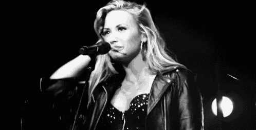 a woman in a leather jacket is singing into a microphone .