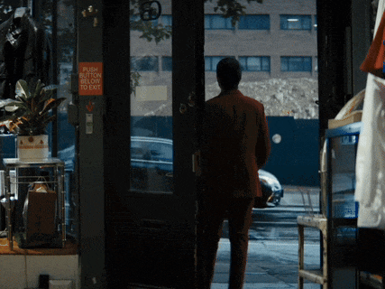 a man in a red suit is standing in front of a door that has a sign on it that says push button to exit