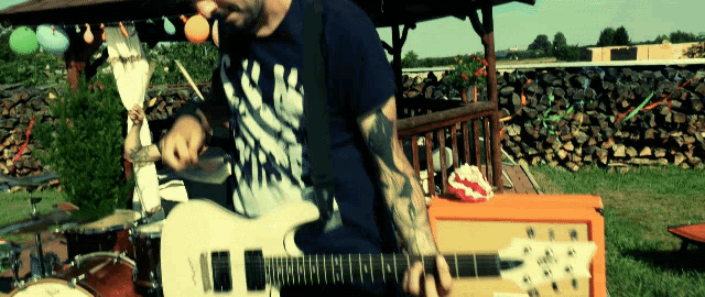 a man playing a guitar in front of a drum set and a pile of wood