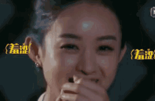 a woman is covering her mouth with her hand and smiling .