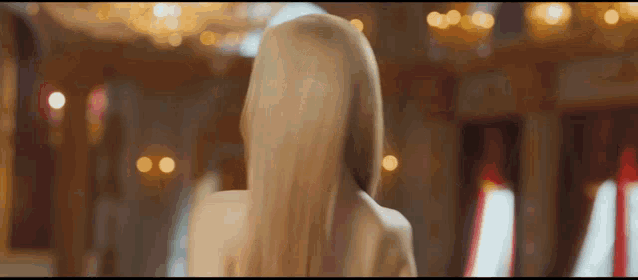 a woman with long blonde hair is standing in a room looking at the camera .