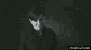a person is standing in the dark with a light shining on their chest .