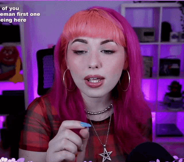 a woman with pink hair is wearing a star necklace and earrings