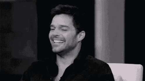 a black and white photo of a man sitting in a chair smiling .