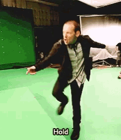 a man is dancing in front of a green screen and the word hold is on the bottom