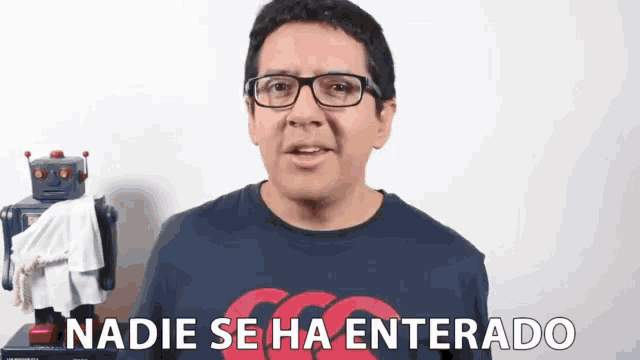 a man wearing glasses says nadie se ha enterado in front of a robot