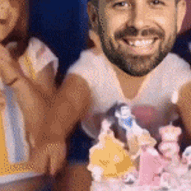 a man with a beard is smiling in front of a cake with princesses on it