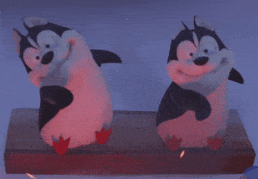 two stuffed penguins are standing next to each other on a box