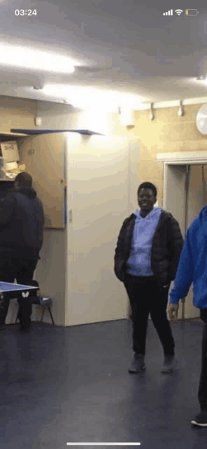 a group of people are standing in a room with the time of 03:24