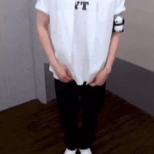 a person wearing a white shirt and black pants is standing in a room .