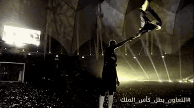 a man is holding a flag in a stadium with arabic writing on it .