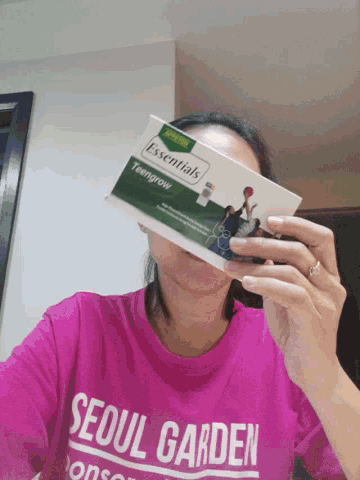 a woman wearing a seoul garden shirt is holding a book