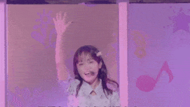 a young girl is standing in front of a purple wall with a microphone in her mouth .
