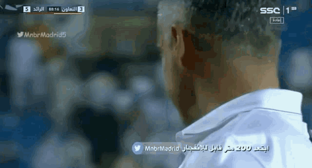 a man in a white shirt is watching a soccer game sponsored by ssc
