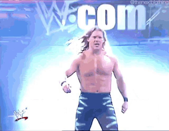 a wrestler is standing in front of a sign that says com