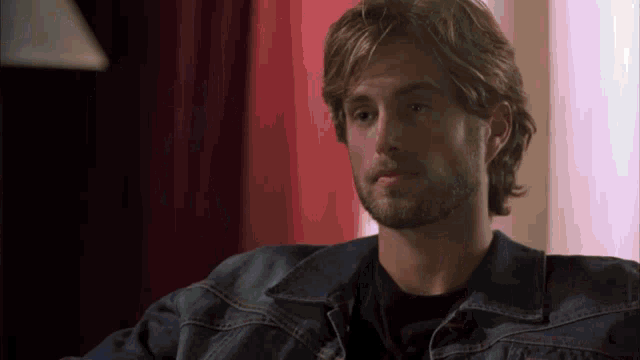 a man with a beard is wearing a denim jacket and a black shirt