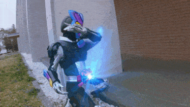a person in a superhero costume is standing in front of a brick wall holding a blue object .