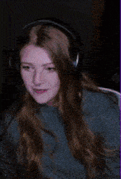 a woman wearing headphones and a blue sweater is smiling .