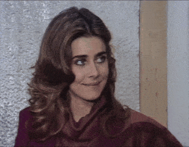 a woman wearing a sweater and a scarf smiles