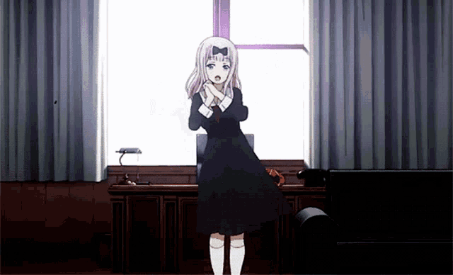 a girl in a black dress is standing in front of a window with her hands folded