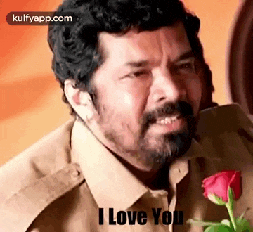 a man with a beard is crying while holding a red rose and saying `` i love you '' .