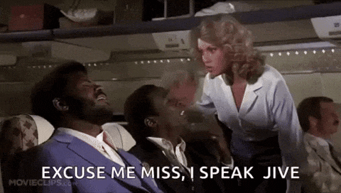 a man in a suit and tie is sitting on an airplane with a woman standing next to him and says excuse me miss