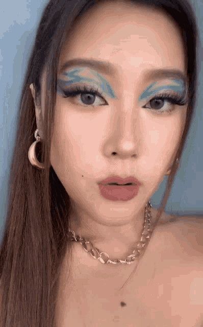 a close up of a woman 's face with makeup and a necklace