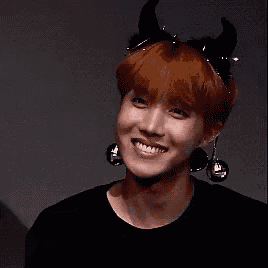 a young man with red hair is wearing a headband with horns and bells around his ears .