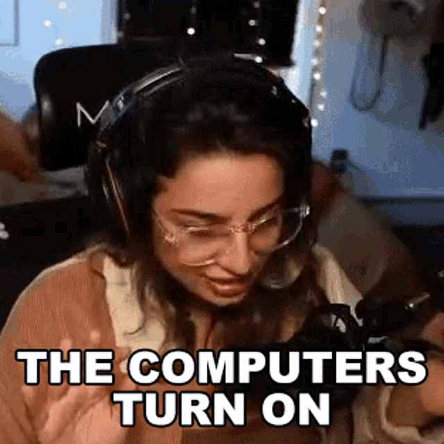 a woman wearing headphones and glasses is sitting in front of a microphone with the words `` the computers turn on '' .