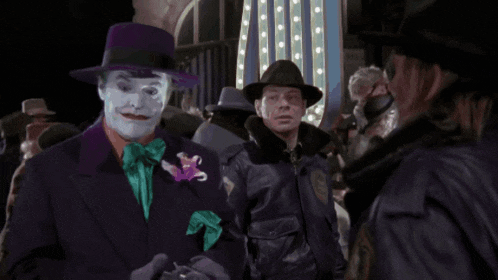 a man in a joker costume stands next to a man in a leather jacket