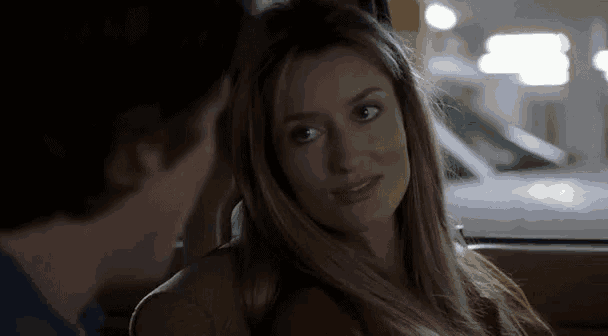 a woman is sitting in the back seat of a car with a man and looking at him .
