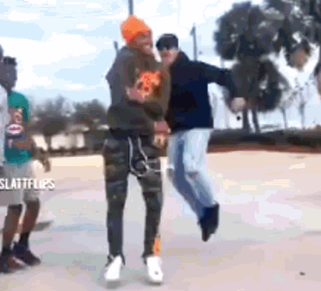 a group of people are standing on a sidewalk and one of them is holding a pizza in his hand .