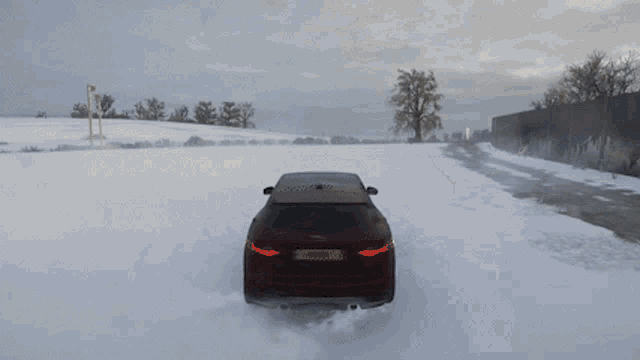 a red suv is driving through the snow on a road