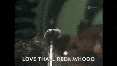 a man is singing into a microphone and saying `` love that red , whooo '' .