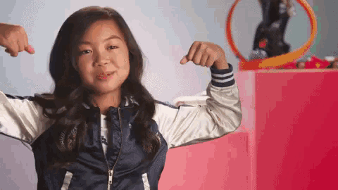 a young girl is flexing her muscles in front of a hot wheels track