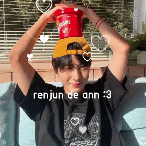 a young man wearing a black shirt and a yellow hat is holding a container of twizzlers