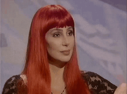 cher is wearing a red wig and making a face .