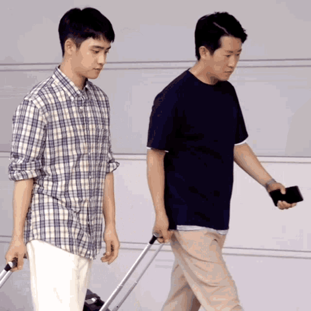 a man in a plaid shirt is pushing a suitcase