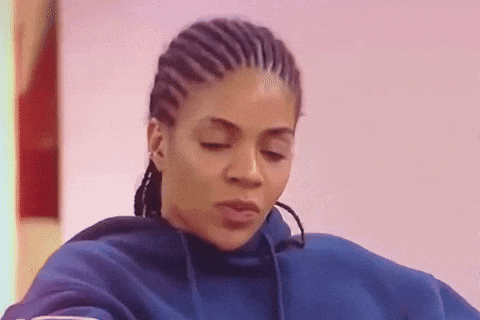 a woman with braids is wearing a blue hoodie and looking at the camera .