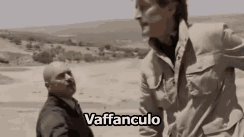 two men are standing next to each other in a field and one of them is talking to the other .