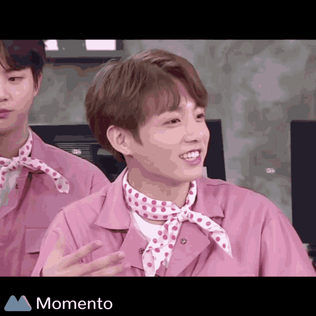 a man in a pink shirt with polka dots around his neck is smiling