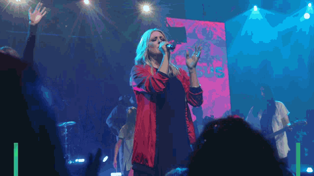 a woman singing in front of a screen that says " jesus "