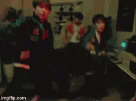 a group of people are dancing in a room with red lights ..