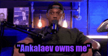 a man is sitting in front of a microphone with the words " ankalaev owns me " above him